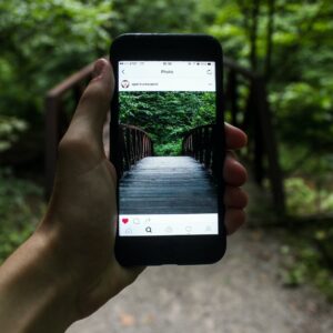person holding smartphone taking picture of bridge during daytime