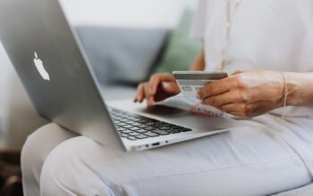 person using a macbook and holding a credit card